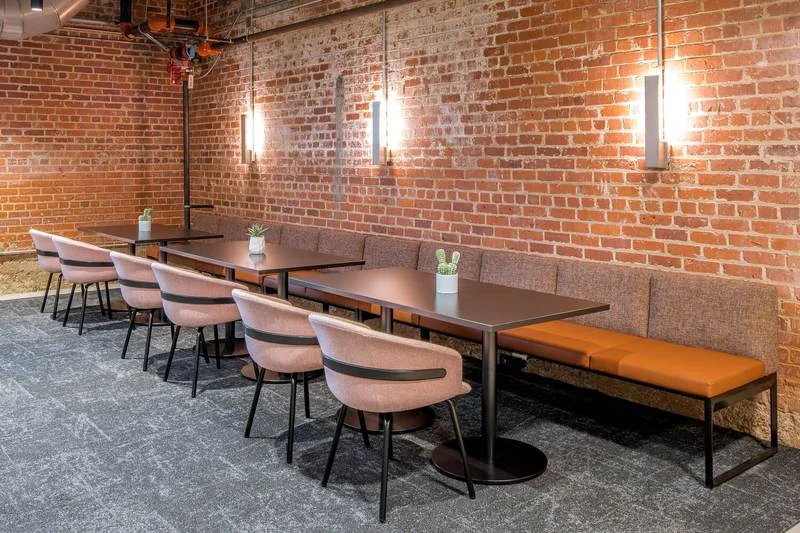 Banquette Seating Cognac banquette with blush chairs along a brick wall