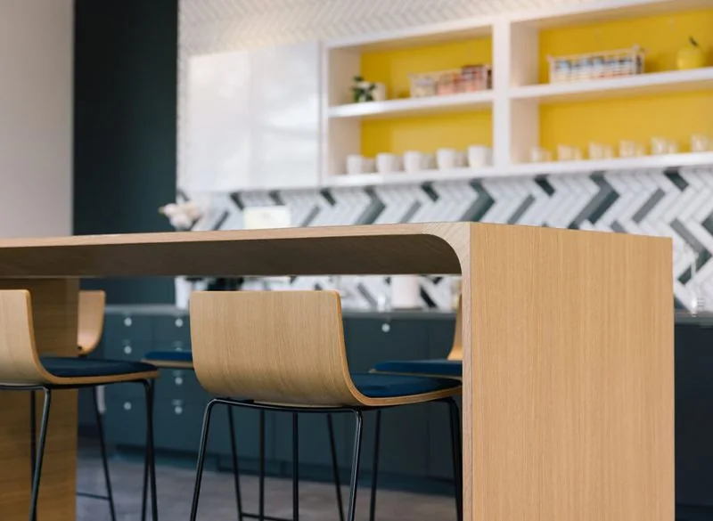 Café Counter Oak counter with bentwood stools against a yellow shelf wall