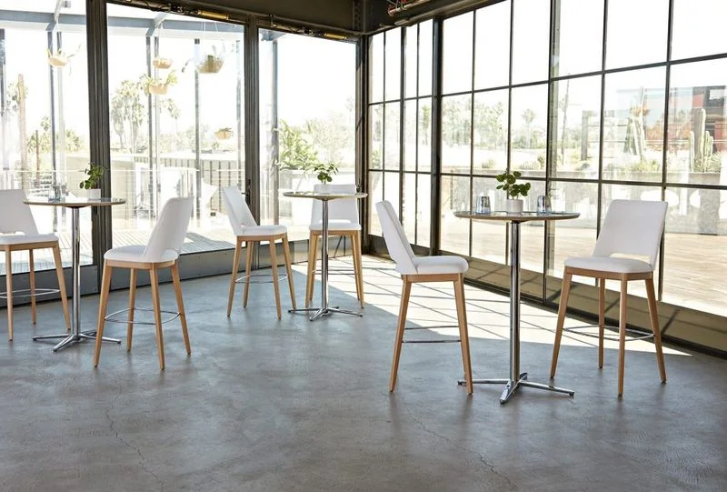 High-Top Café Seating White bar stools at high café tables in a sunlit space