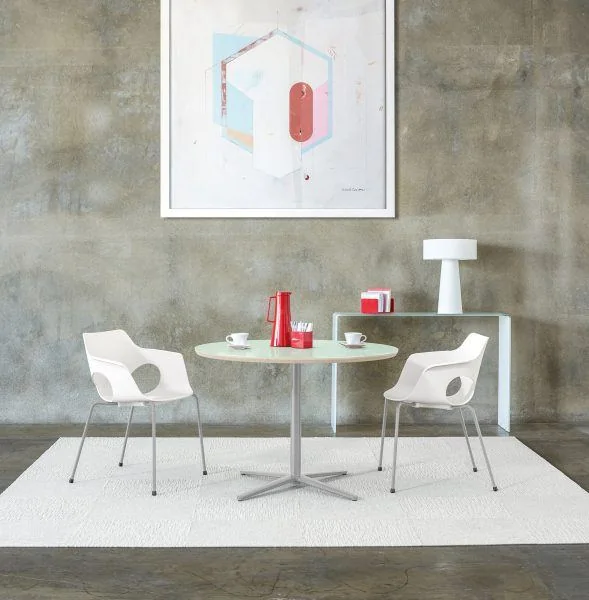 Café Table and Chairs White shell chairs at a round café table against a concrete wall