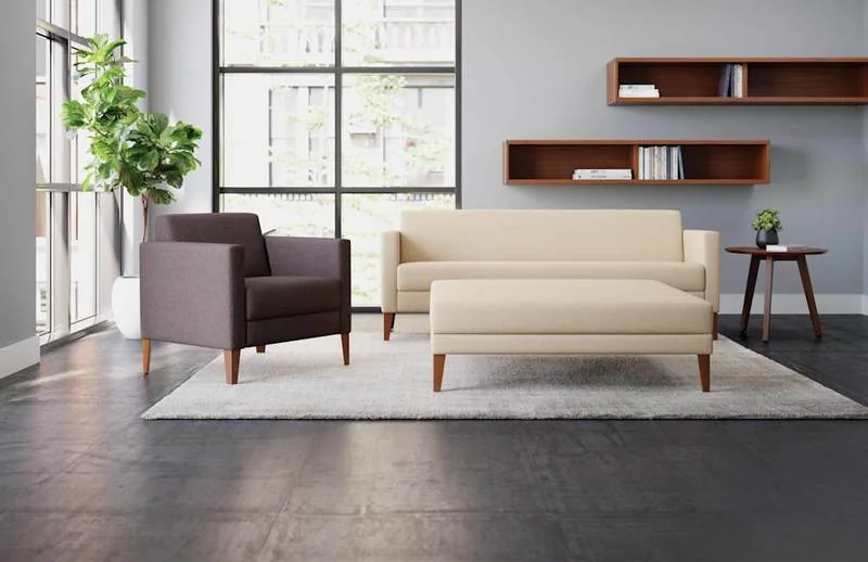 Beige sofa and plum lounge chairs beside wall shelving
