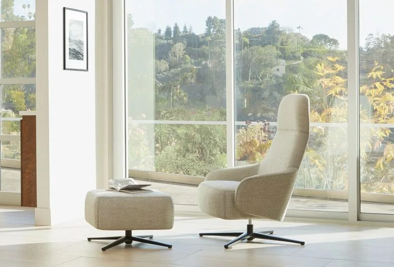 Cream high-back lounge chairs with ottoman in a bright corner
