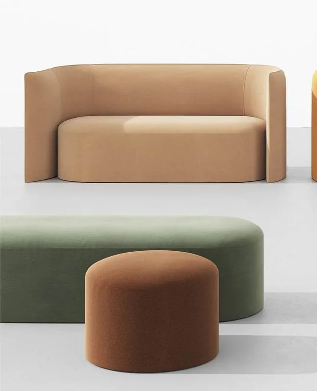 Tan sofa with a green bench and rust pouf