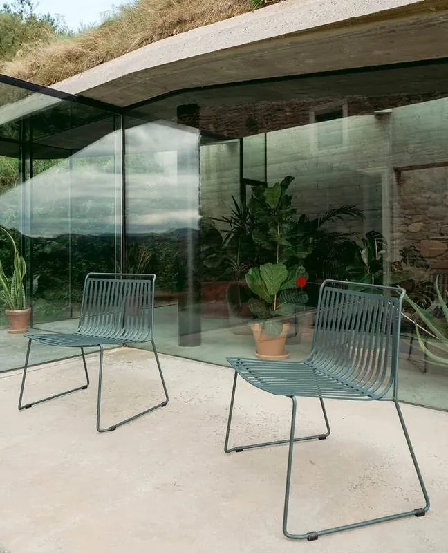 Patio Chairs Teal wire chairs on a glass-walled patio