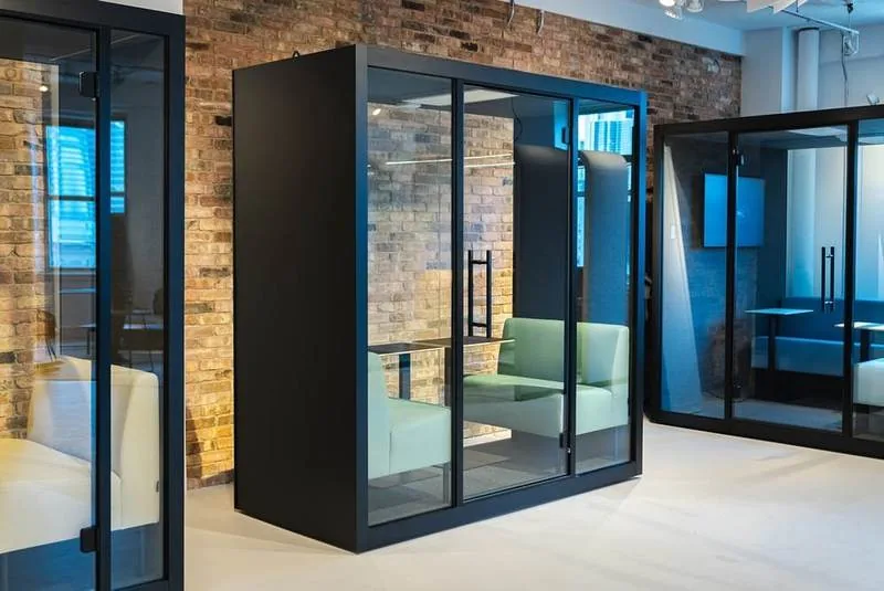 Glass Meeting Pods Two black-frame glass meeting pods against a brick wall