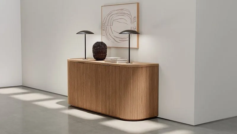 Curved oak tambour credenza with a single table lamp
