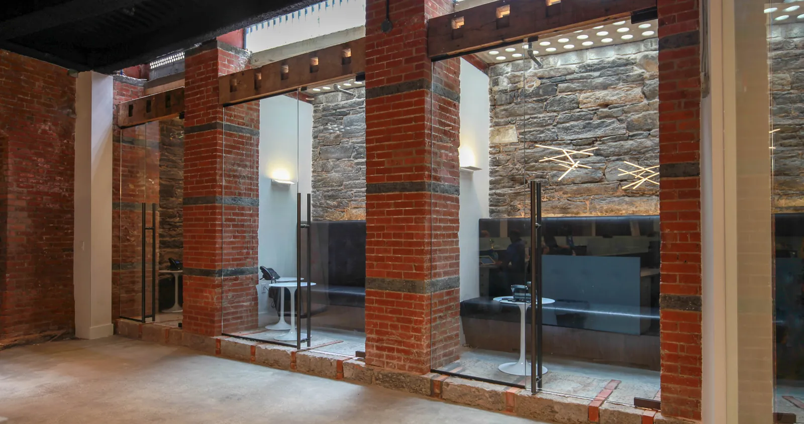 Glass Walls in Historic Space Black-framed glass walls between brick piers in a converted building