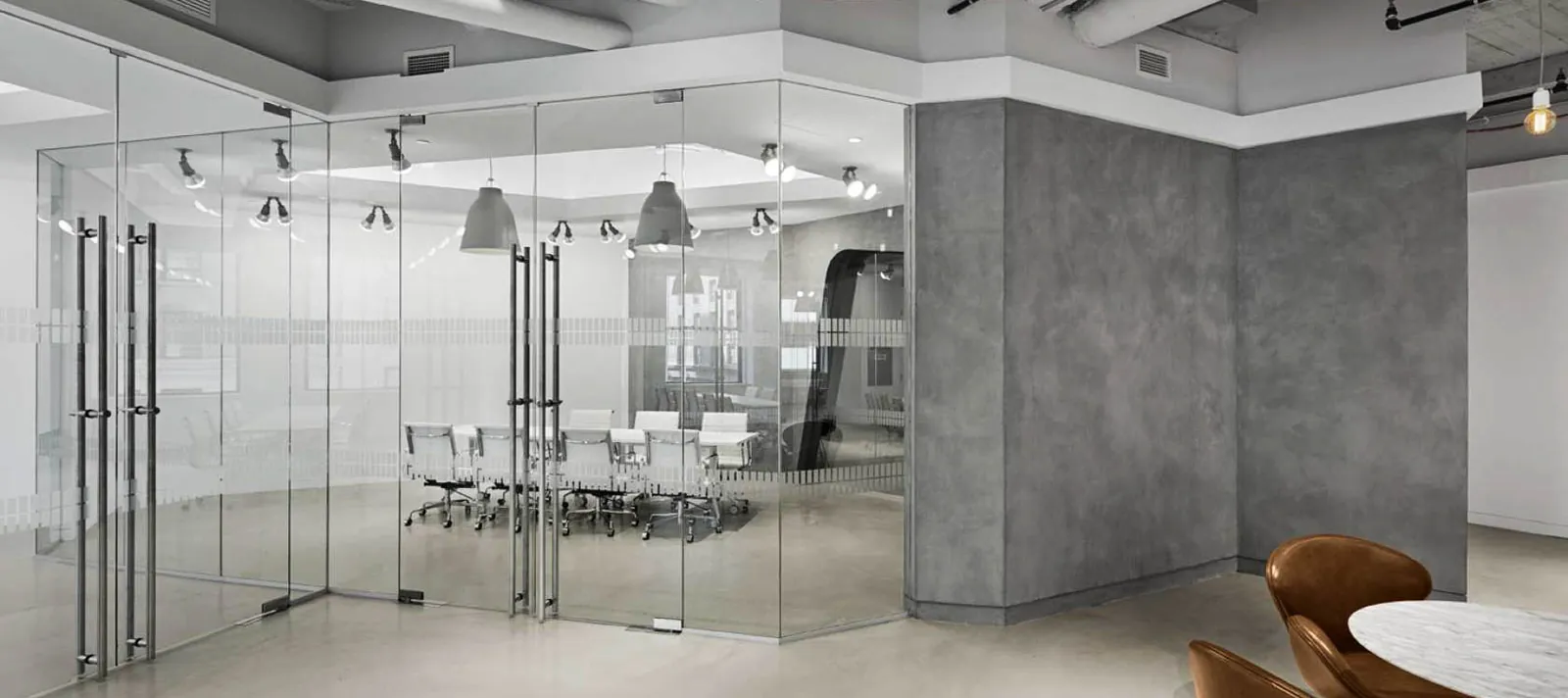 Glass Conference Room Frameless glass conference room with pivot doors in a loft office