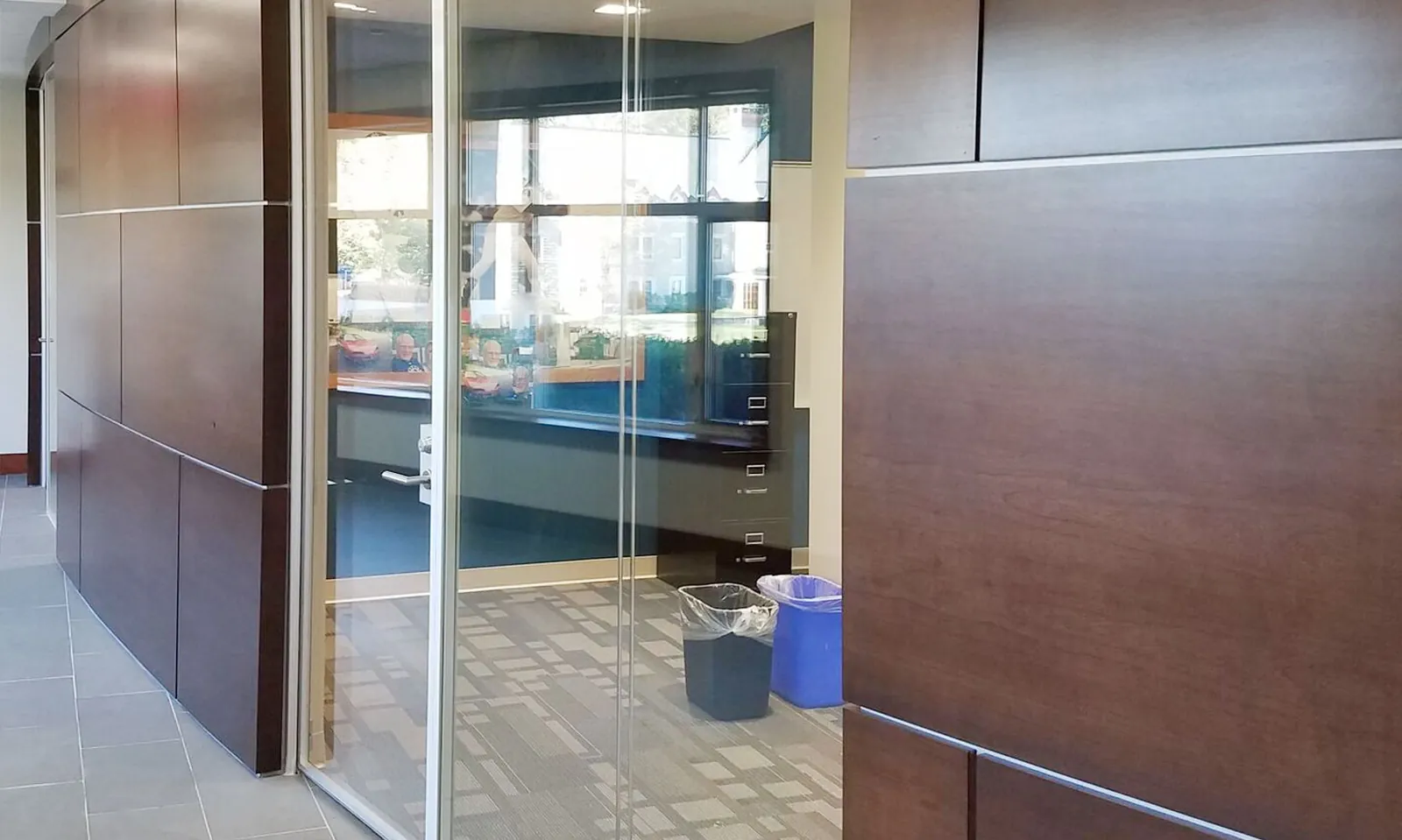 Glass Office Entry Frameless glass entry between dark wood wall panels